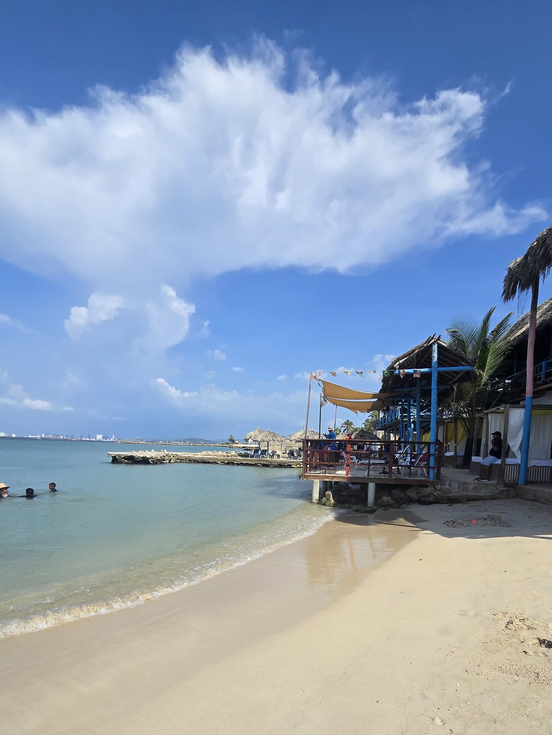 Orilla de arena de Paraíso del Sol con el deck de madera del club y el mar a la izquierda.